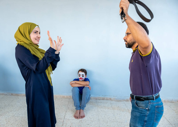 Chlapec se dívá, jak se jeho rodiče hádají a jeho otec drží pásek - Fotografie, Obrázek