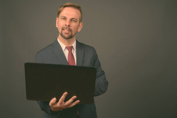 Blond bearded businessman with goatee against gray background - Foto, afbeelding