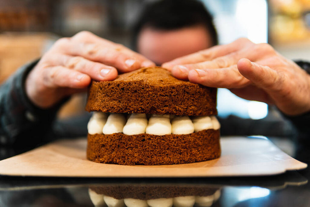 Close-up of a baker's hands mounting a cake - Photo, image