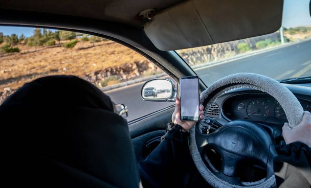 Arabská muslimská žena řídící auto při použití svého chytrého telefonu - Fotografie, Obrázek