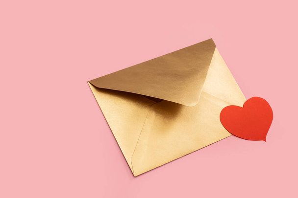 Golden paper envelope with red heart isolated on pink background - Photo, image