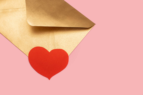 Golden paper envelope with red heart isolated on pink background - Foto, Imagen