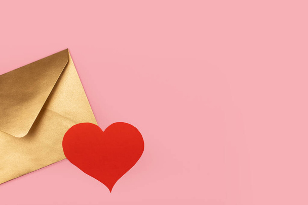 Golden paper envelope with red heart isolated on pink background - Fotografie, Obrázek