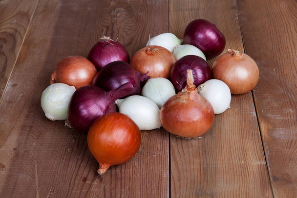 White, yellow and red onions on a wooden background. - Foto, Imagem