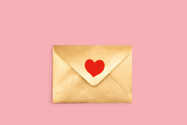 Golden paper envelope with red heart isolated on pink background - Fotoğraf, Görsel