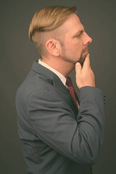 Hombre de negocios barbudo rubio con perilla sobre fondo gris - Foto, Imagen