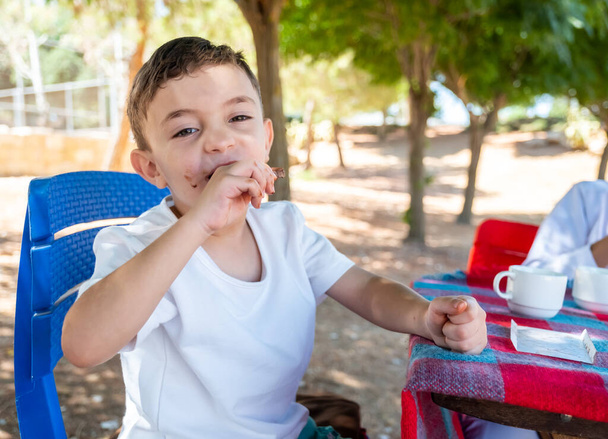 Pequeño chico árabe disfrutando comiendo chocolate solo. - Foto, imagen