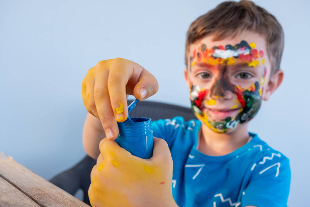 Garçon jouer avec les couleurs en utilisant ses mains et son visage - Photo, image