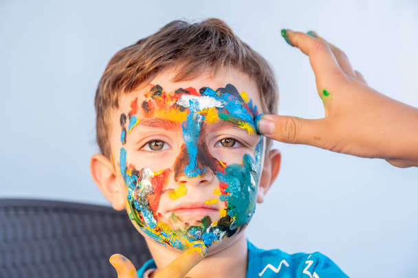 Boy playing with colors using his hands and his face - Φωτογραφία, εικόνα