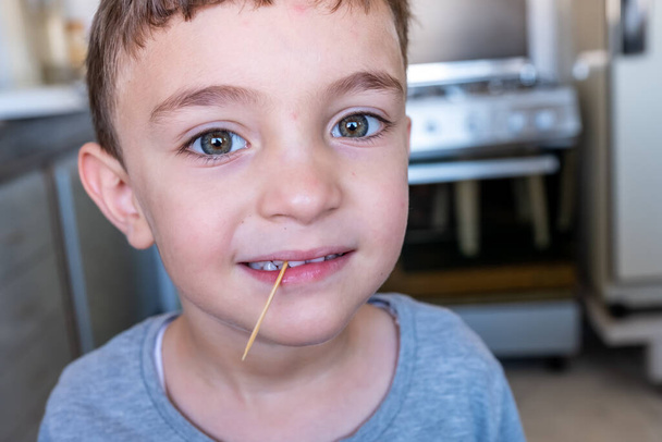 Το αγόρι έχει μια οδοντογλυφίδα στα δόντια του. - Φωτογραφία, εικόνα