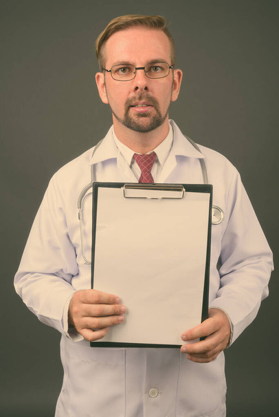 Hombre rubio barbudo médico con perilla sobre fondo gris - Foto, Imagen