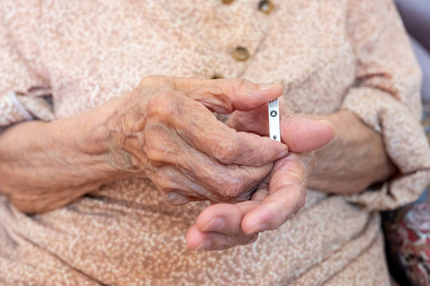 Stará žena drží hladinu cukru měřicí čip - Fotografie, Obrázek