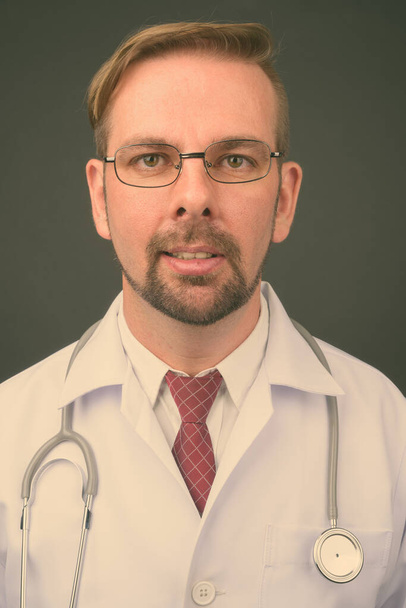 Блондинка бородатий чоловік лікар з ґоаті на сірому фоні
 - Фото, зображення