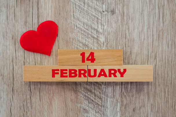 Valentinstag-Konzept. Rotes Herz und die Inschrift "14. Februar" auf Holzklötzen - Foto, Bild