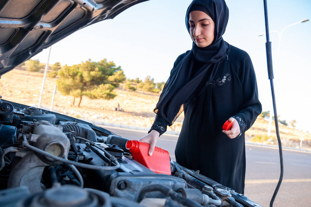Mujer árabe vertiendo aceite en su motor de coche - Foto, Imagen