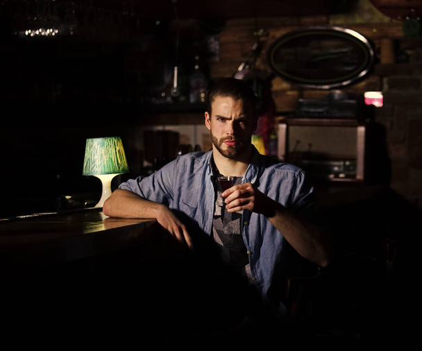 Guy at bar counter drinks glass of shot or liqueur. - Фото, зображення