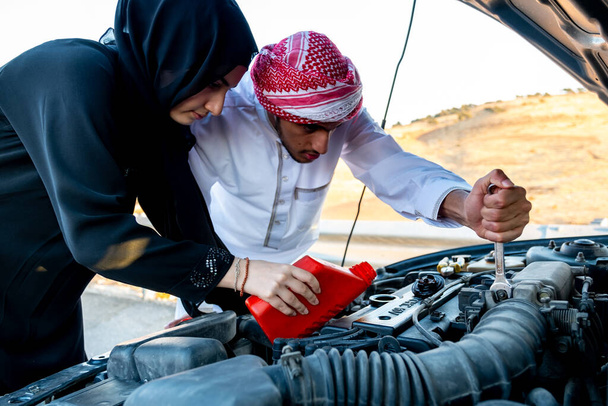 Арабская женщина и ее муж заливают масло в двигатель автомобиля - Фото, изображение