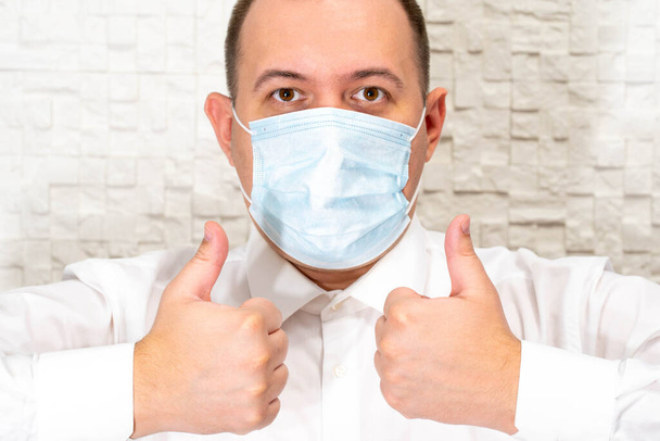 The doctor in a mask and rubber gloves makes a gesture. Gesture as a symbol of approval of prevention and protection - Foto, Imagen