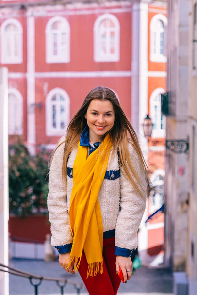 dziewczyna w stylowych ubraniach patrzy w aparat i chodzi ulicami Lizbony. zbliżenie. - Zdjęcie, obraz