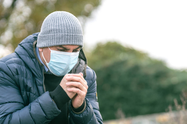Nieprawidłowy sposób kichania lub kaszlenia w ochronną maskę medyczną na zewnątrz. Zapobieganie rozprzestrzenianiu się choroby Coronavirus 2019 (COVID-19) - Zdjęcie, obraz