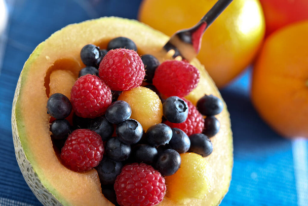 Canteloupes половинки со смешанными фруктами внутри на столе - Фото, изображение