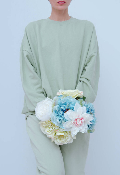 Young Beautiful Girl Standing In Room with Flowers In Her Hands. Fresh aqua menthe colours trends. Spring summer collection - Фото, зображення