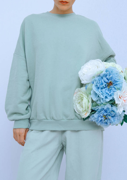 Beautiful Girl Standing In white Room with Flowers In Her Hands. Fresh aqua menthe colours trends. Spring summer collection - Valokuva, kuva