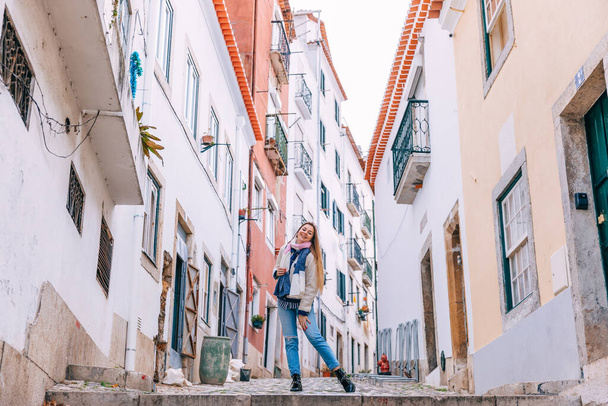 chica posando entre edificios en una calle estrecha de Lisboa. mira a la cámara. - Foto, Imagen