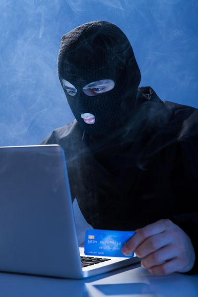 Hacker Holding Credit Card While Using Laptop - Fotó, kép