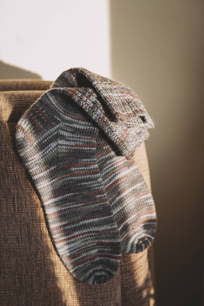 Paire de chaussettes tricotées à la main sur le canapé à la lumière du soleil. Couleurs naturelles.  - Photo, image