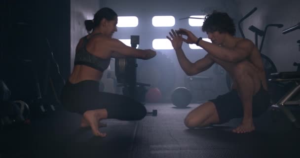 Mann und Frau strecken sich aus Kniebeugen in Turnhalle - Filmmaterial, Video