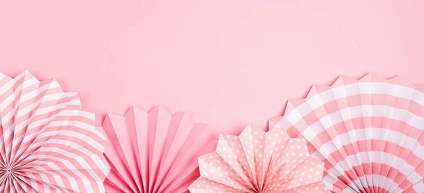 Festive party background banner with pink paper circle fans over pastel background. Festival, birthday, baby shower decoration. Top view - Photo, Image