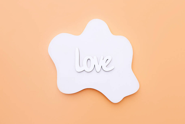Ξύλινη λέξη Αγάπη σε λευκό σκυρόδεμα γεωμετρικό σχήμα σε πορτοκαλί φόντο, πάνω όψη - Φωτογραφία, εικόνα