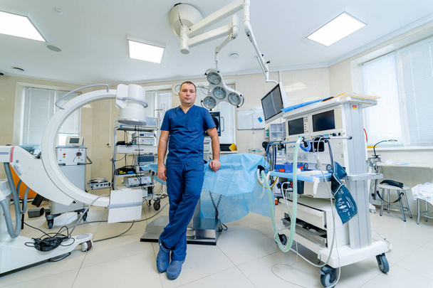 Surgeon is posing in an operating room. Hospital background. Male doctor at work looking at camera. Medical issues. - Photo, Image