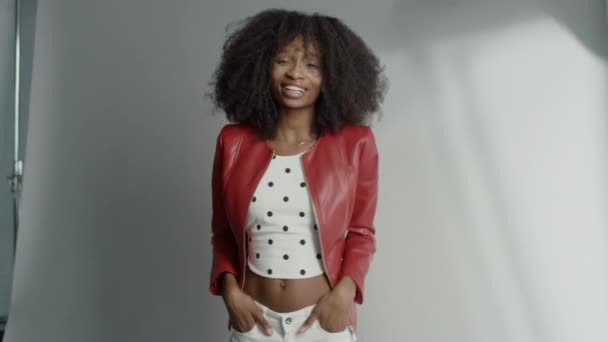 Attractive Black Girl with Lush Curly Hair Posing for a Fashion Magazine Photoshoot. Beautiful Girl Smiles Playfully and Acts for Photo Shoot Made in Professional Studio. Medium Shot - Filmmaterial, Video