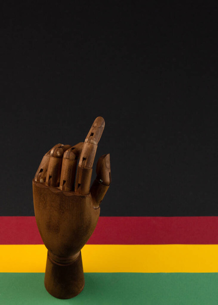 February Black History Month. Brown wooden hand on Paper geometric black, red, yellow, green background. Copy space, place for your text. Top view. - Photo, Image