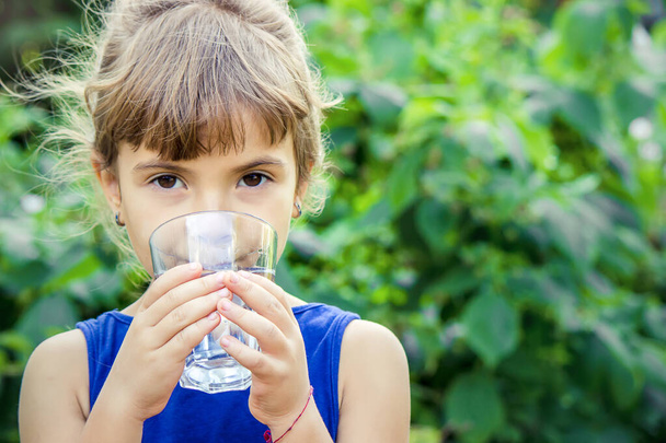 Το παιδί πίνει καθαρό νερό το καλοκαίρι. Επιλεκτική εστίαση. Άνθρωποι. - Φωτογραφία, εικόνα