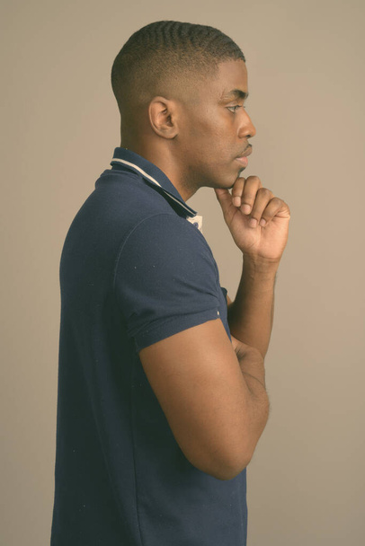 Young handsome African man wearing blue polo shirt against gray background - Φωτογραφία, εικόνα