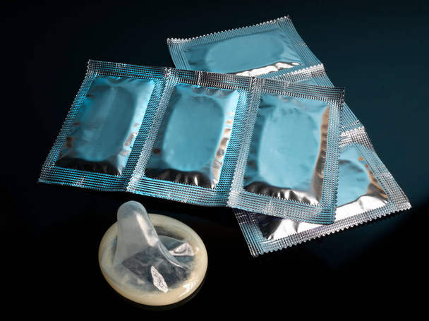 Opened condom package on a black background - Foto, imagen
