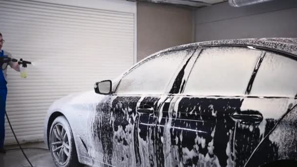 Процесс мытья машины. Пенящееся моющее средство закрывает боковую сторону автомобиля, очищает его от грязи и пыли. - Кадры, видео