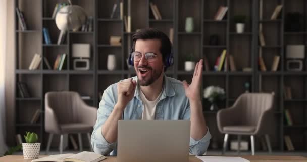Man resting at workplace sing song listens music through headphones - Séquence, vidéo