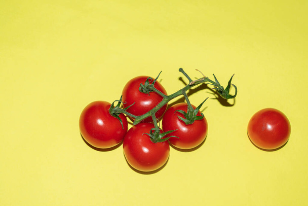 Ramo de tomates cereja suculentos em um fundo amarelo - Foto, Imagem