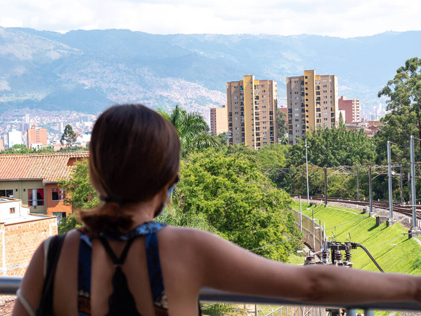Eine brünette Frau betrachtet den Blick auf die Gebäude, Berge in Medellin, Kolumbien - Foto, Bild