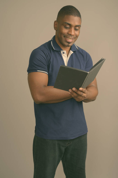 Mladý pohledný africký muž na sobě modré polo košile proti šedému pozadí - Fotografie, Obrázek