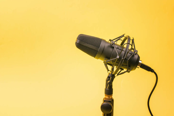 Modern kondenzátor mikrofon egy állványon sárga háttérrel. Hangfelvevő berendezés. - Fotó, kép