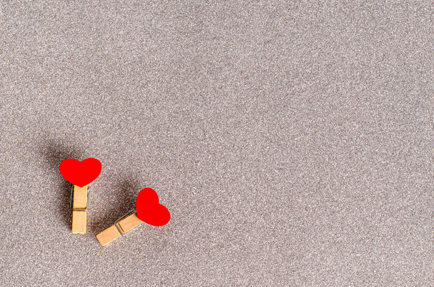 Decorative clothespins with red hearts for Valentines Day on a gray glittering background. - Fotografie, Obrázek