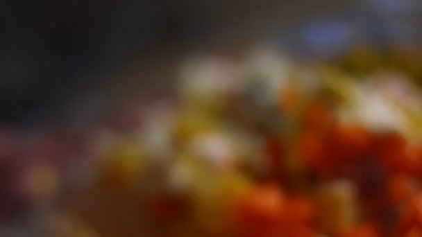 Valmistelu venäläinen perinteinen salaatti Olivier. Ainesosien sekoittaminen lasikulhossa - vihreät herneet, perunat, makkara, porkkana, munat, majoneesi. 4K-video. Makro näkymä - Materiaali, video
