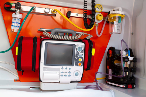 Defibrillator is seend inside of an ambulance. Defibrillation is a treatment for life-threatening cardiac dysrhythmias delivering a dose of electric current to the heart. - Foto, afbeelding