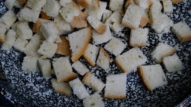 Rebanadas de pan blanco cortadas en cubitos, fritas en sartén y volteadas con espátula para hacer croutons. Cocina casera. Primer plano. - Metraje, vídeo