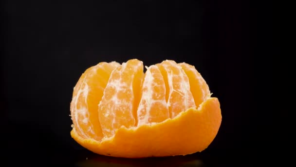 Jeden pomarańczowy mandarynka cytrusowa przędzenia w makro. Owoce w centrum po ciemku - Materiał filmowy, wideo